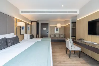 a hotel room with two beds and a flat screen tv at My Beach Resort Phuket, Panwa Beach in Panwa Beach