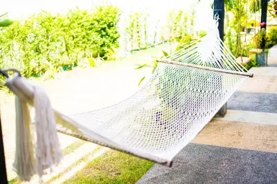 a hammock sitting on the grass in a yard at ChillHub Hostel Phuket in Bang Tao Beach