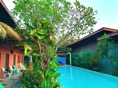 a swimming pool with a tree next to a house at Six Pack Cottage in Chalong