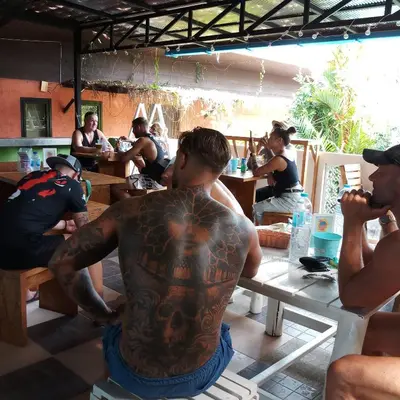 a man with a tattoo on his back sitting at a table at Six Pack Cottage in Chalong