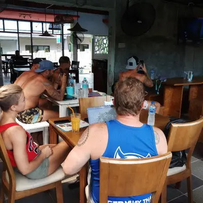 a group of men sitting at a table in a restaurant at Six Pack Cottage in Chalong