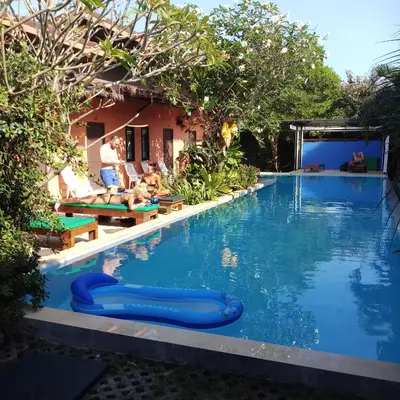 a pool at a resort with people laying on chairs at Six Pack Cottage in Chalong