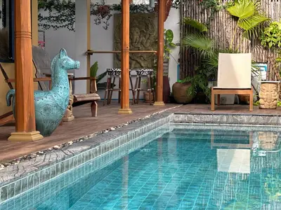 a swimming pool with a peacock statue next to a house at The Luna in Nai Yang Beach