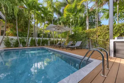 a swimming pool with a deck and chairs and palm trees at VILLA PULAU 3 bedroom Baan Bua Estate in Nai Harn Beach