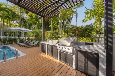 an outdoor kitchen with a grill and a swimming pool at VILLA PULAU 3 bedroom Baan Bua Estate in Nai Harn Beach