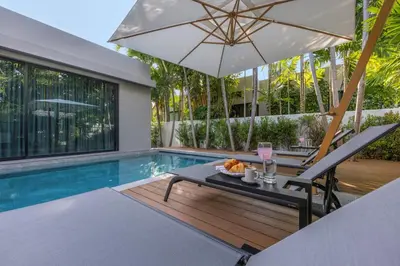 a patio with a table and umbrella next to a swimming pool at VILLA PULAU 3 bedroom Baan Bua Estate in Nai Harn Beach