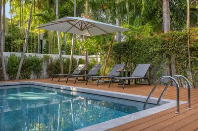 a swimming pool with chairs and an umbrella at VILLA PULAU 3 bedroom Baan Bua Estate in Nai Harn Beach
