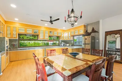 a kitchen with a wooden table and chairs at Happy Family Villa 2 in Chalong