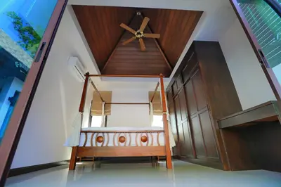 a bed in a room with a wooden ceiling at Naiharn Beach Villa in Nai Harn Beach