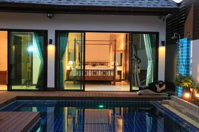 a person laying on the ground next to a swimming pool at Naiharn Beach Villa in Nai Harn Beach