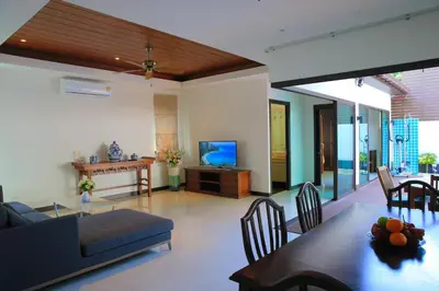 a living room with a couch and a tv at Naiharn Beach Villa in Nai Harn Beach
