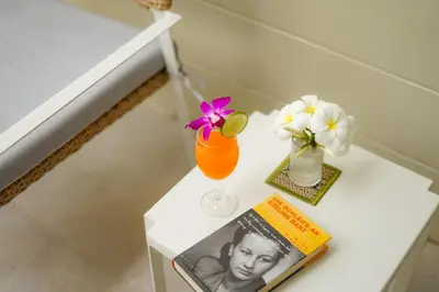 a table with a book and a vase with flowers and a magazine at Impress Resort in Thalang