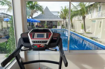 a treadmill in front of a window with a swimming pool at Impress Resort in Thalang