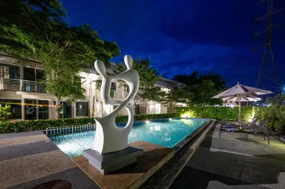 a statue next to a swimming pool at night at Impress Resort in Thalang