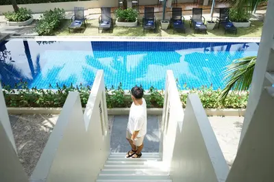 a woman walking down the stairs in front of a swimming pool at Impress Resort in Thalang