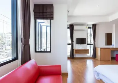 a living room with a red couch and a bed at Buk Inn Hotel SHA Plus in Kamala Beach