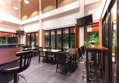 a restaurant with a bar with tables and chairs at Buk Inn Hotel SHA Plus in Kamala Beach