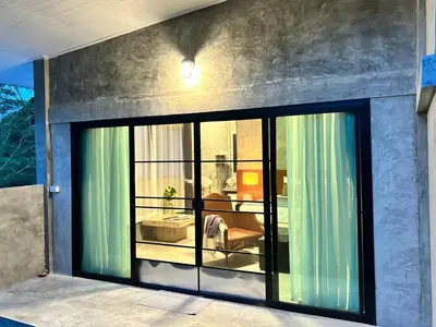 a room with a large window in a house at Phuchada Residence in Nai Yang Beach