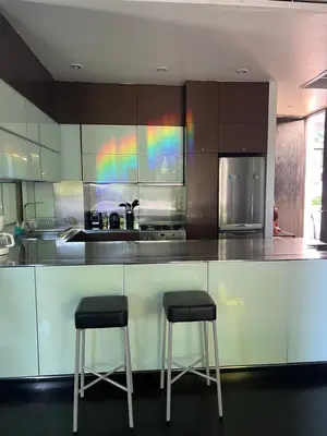 a kitchen with two stools at a counter with a rainbow at Kata Gardens Apartments in Kata Beach