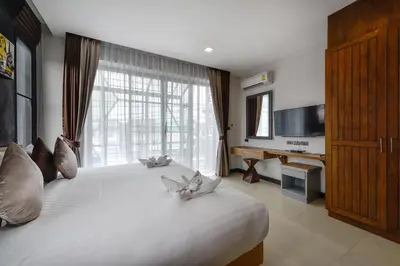 a bedroom with a large white bed with a large window at Casa Bella Phuket in Chalong