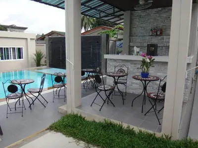 a patio with tables and chairs next to a swimming pool at Thuan Resort in Rawai Beach