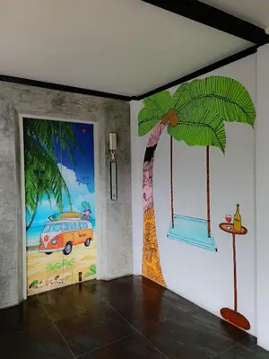 a room with a painting of a palm tree on the wall at OneLoft Hotel in Karon Beach