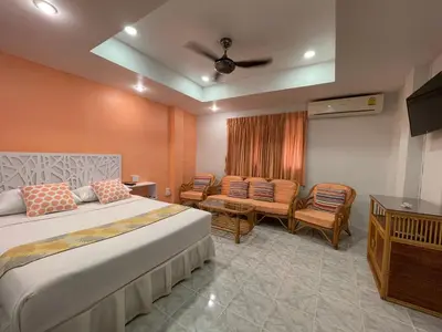 a hotel room with a bed and chairs and a window at Summer Breeze Hotel in Patong Beach