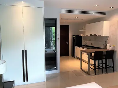 a kitchen with white cabinets and a table with chairs at Emerald Terrace Apartments by Lofty in Patong Beach