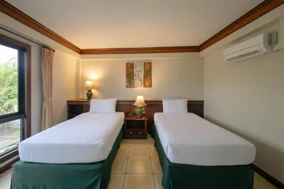 two beds in a room with a window at Erawan Phangnga Hotel, Natai Beach in Khok Kloi