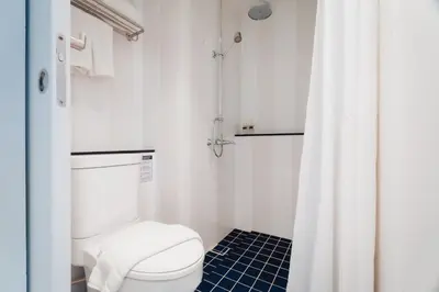a white bathroom with a toilet and a shower at Xinlor House - Phuket Old Town in Phuket Town