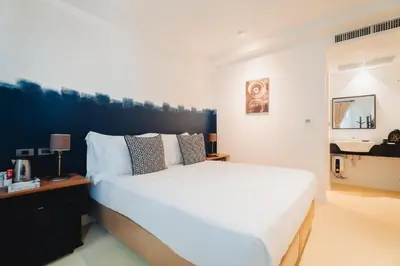 a bedroom with a large white bed with a black headboard at Xinlor House - Phuket Old Town in Phuket Town