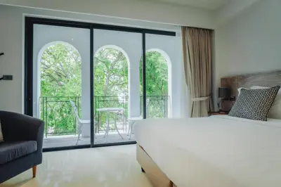 a bedroom with a white bed and a balcony at Xinlor House - Phuket Old Town in Phuket Town