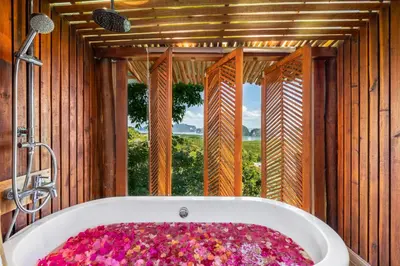 a bathroom with a bath tub with a large window at Sametnangshe Boutique in Phangnga