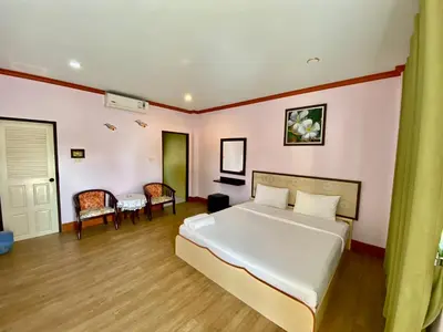a bedroom with a large white bed and a table at Pachumas Hotel in Karon Beach