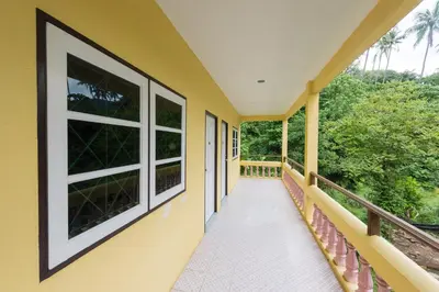 a balcony of a house with yellow walls and windows at Pachumas Hotel in Karon Beach