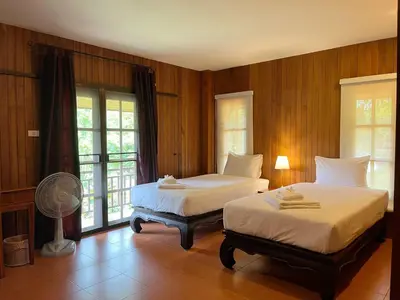 two beds in a room with wooden walls and windows at Symphony Villa in Nai Harn Beach