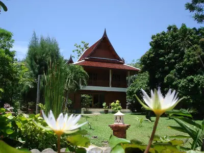 a house in a garden with flowers in the foreground at Symphony Villa in Nai Harn Beach