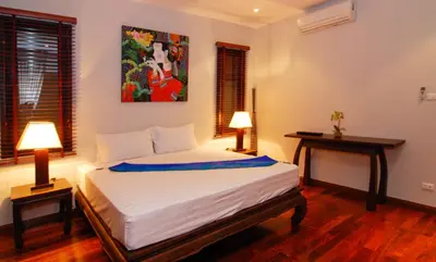 a bedroom with a bed and two tables and a painting at Villa Susu by Holiplanet in Rawai Beach