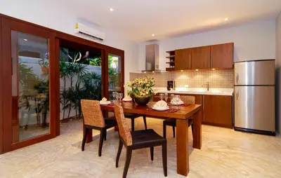 a kitchen with a wooden table with chairs and a refrigerator at Villa Susu by Holiplanet in Rawai Beach