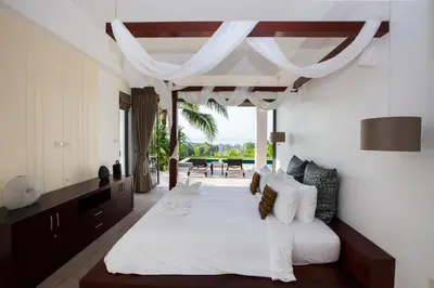 a bedroom with a large white bed and a table at Baan Phukhao in Klong Muang Beach