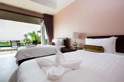 a bedroom with two beds with white sheets and a window at Baan Phukhao in Klong Muang Beach