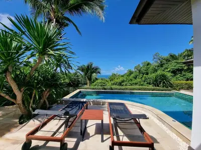 a resort with a pool and chairs and palm trees at Baan Phukhao in Klong Muang Beach