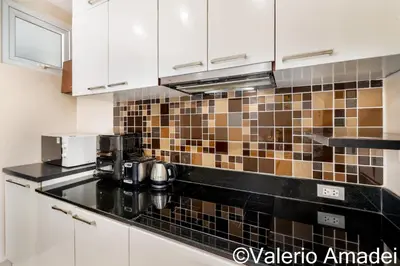a kitchen with white cabinets and black counter tops at Sea & Sky Karon Beach by PHR in Karon Beach