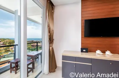 a living room with a tv and a balcony at Sea & Sky Karon Beach by PHR in Karon Beach