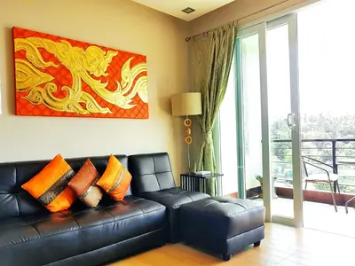 a black leather couch in a living room with a painting at Sea & Sky Karon Beach by PHR in Karon Beach