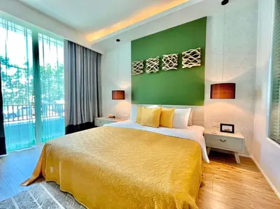 a bedroom with a large bed with a green wall at Mukrada House Boutique Hometel Krabi in Klong Muang Beach