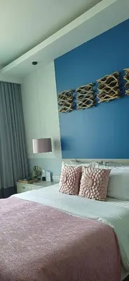 a bedroom with a bed with pink sheets and a blue wall at Mukrada House Boutique Hometel Krabi in Klong Muang Beach