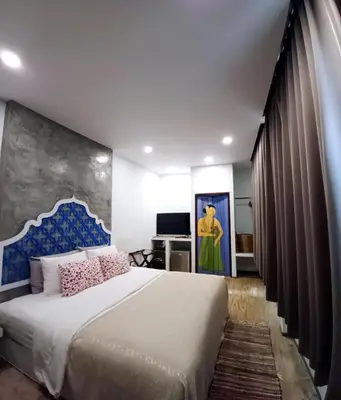 a bedroom with a large bed and a painting on the wall at Mukrada House Boutique Hometel Krabi in Klong Muang Beach
