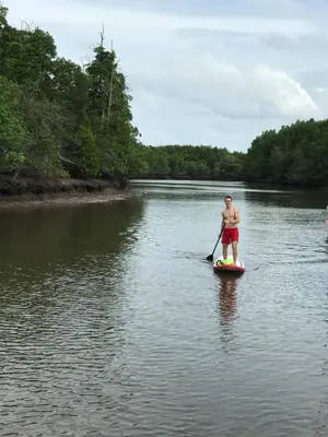 a man standing on a paddle board on a river at Activities Resort in Ko Yao Yai