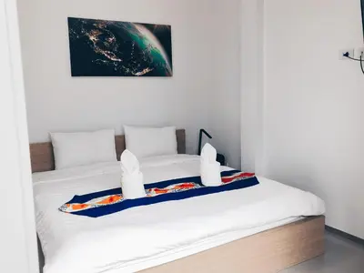 two beds in a white room with a picture on the wall at Ban Don Holidayhome in Thalang